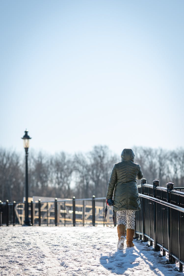 Woman Crossing Snowy Bridge In Winter 