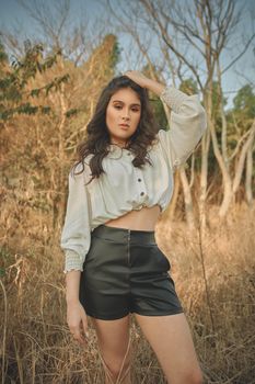 A fashionable woman poses confidently in an outdoor setting, showcasing trendy style.