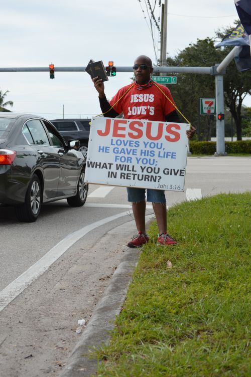 Free Man holding a Bible and religious sign on street corner promoting faith. Stock Photo