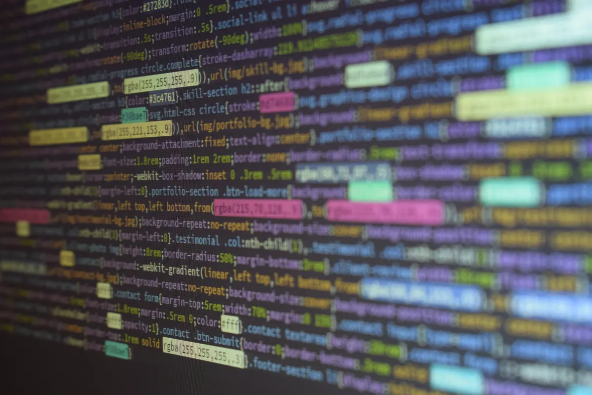 Lines of colorful source code on a dark monitor, shot at an angle.