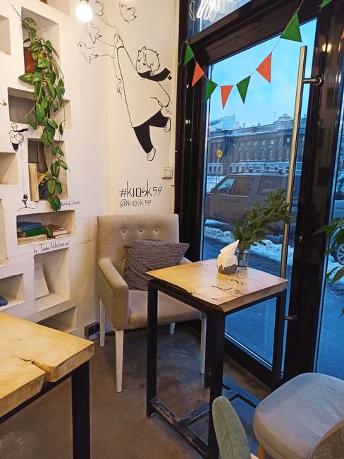A cozy cafe corner featuring a playful wall mural and indoor plants in Saint Petersburg.