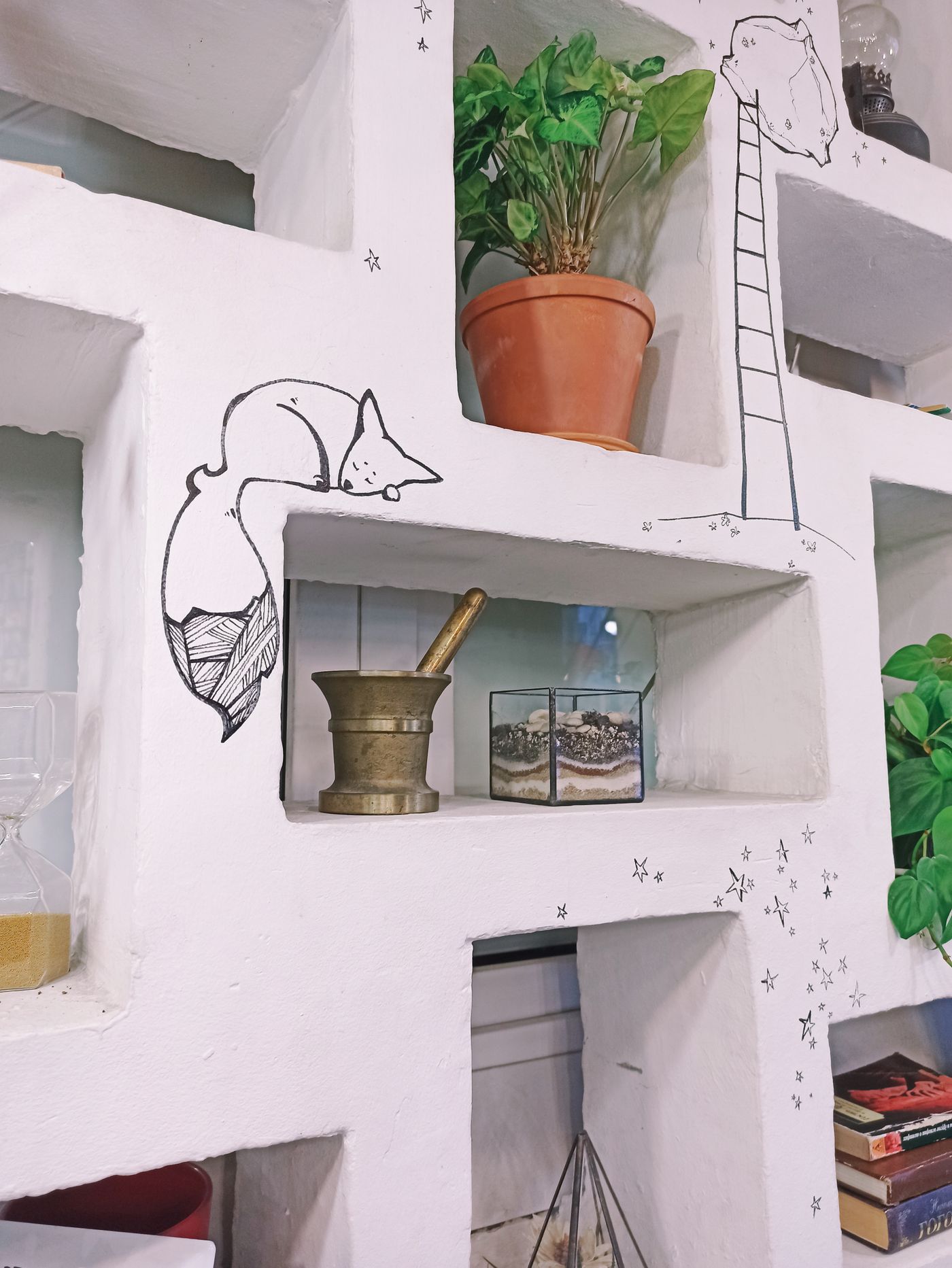 A neatly styled shelf with plants and artwork in a bright home