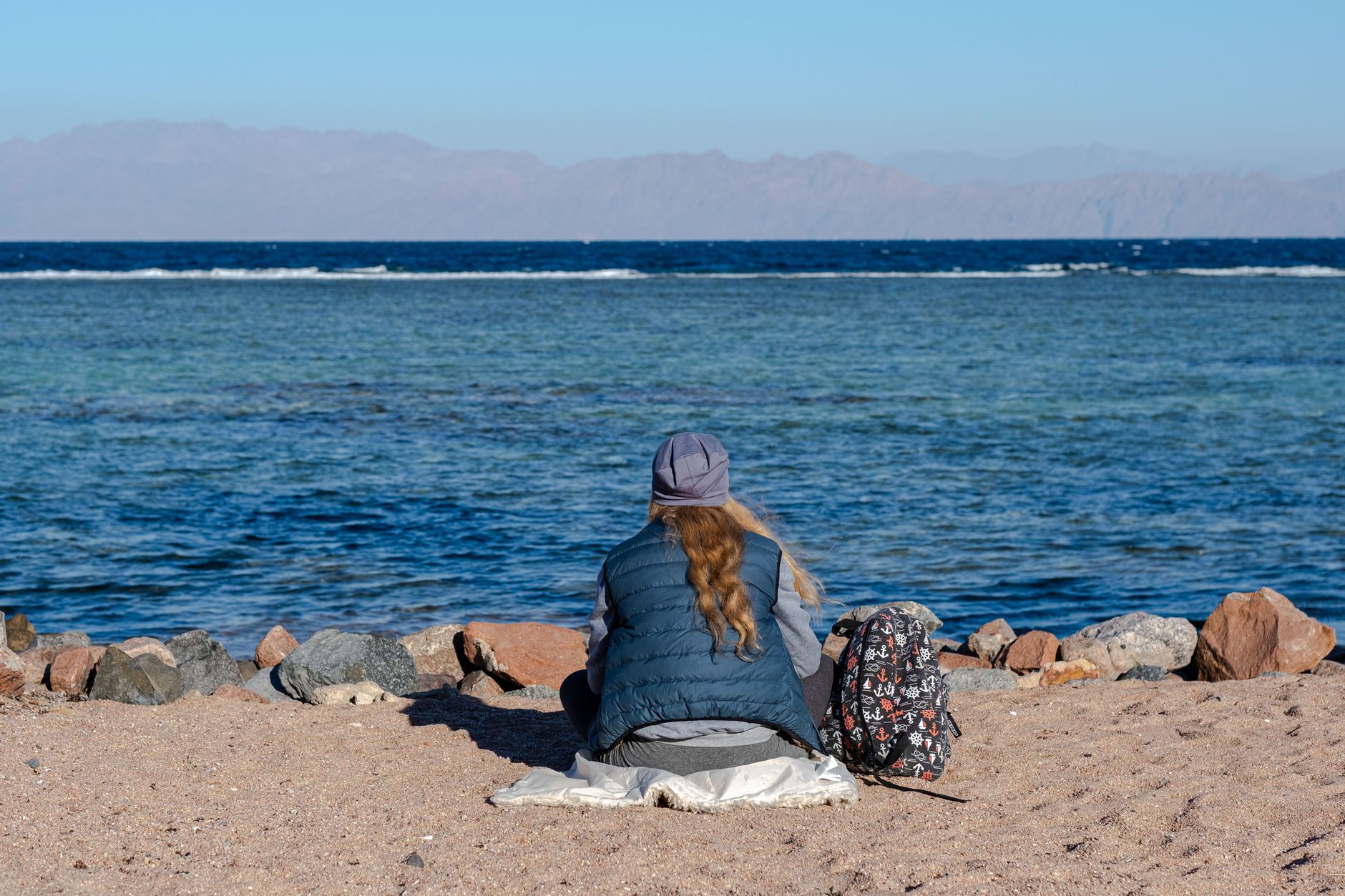 A person sitting by the tranquil seaside, enjoying the scenic view of the ocean.