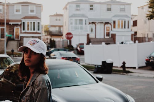 Неглубокая фотография женщины в серой джинсовой куртке, стоящей возле машины