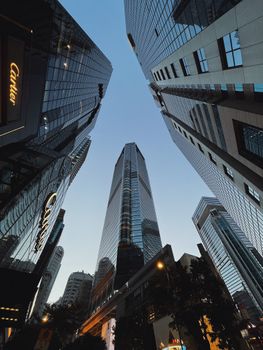 Dramatic upward view of skyscrapers, reflecting the blue sky, showcasing urban architecture.