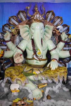 A beautifully decorated Lord Ganesha statue with multiple arms, captured during a festival celebration.