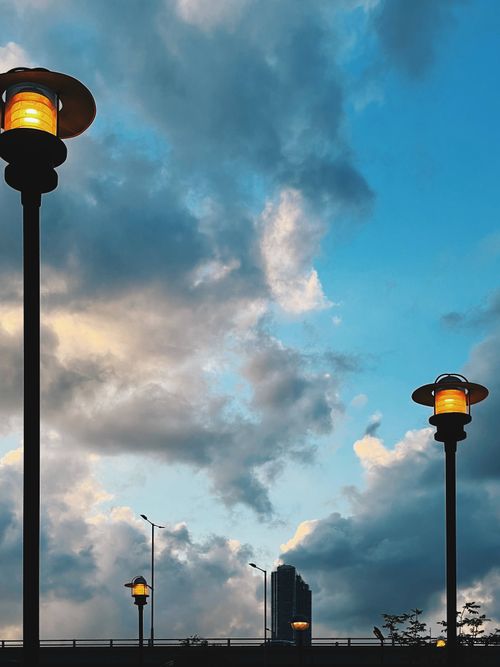 Free Low angle view of illuminated street lamps against a cloudy evening sky. Stock Photo