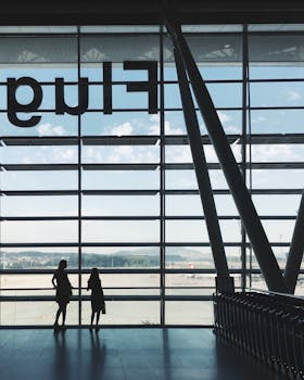 Two people silhouette against large terminal windows at an airport in Hong Kong.