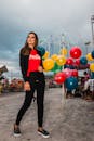 一位时尚女性在充满活力的户外狂欢节上，摆着姿势，身边环绕着五颜六色的气球