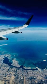 Stunning aerial shot of a coastal city and sea viewed from an airplane window.