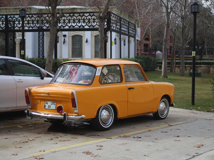 Old Yellow Car Parked Near A Park 