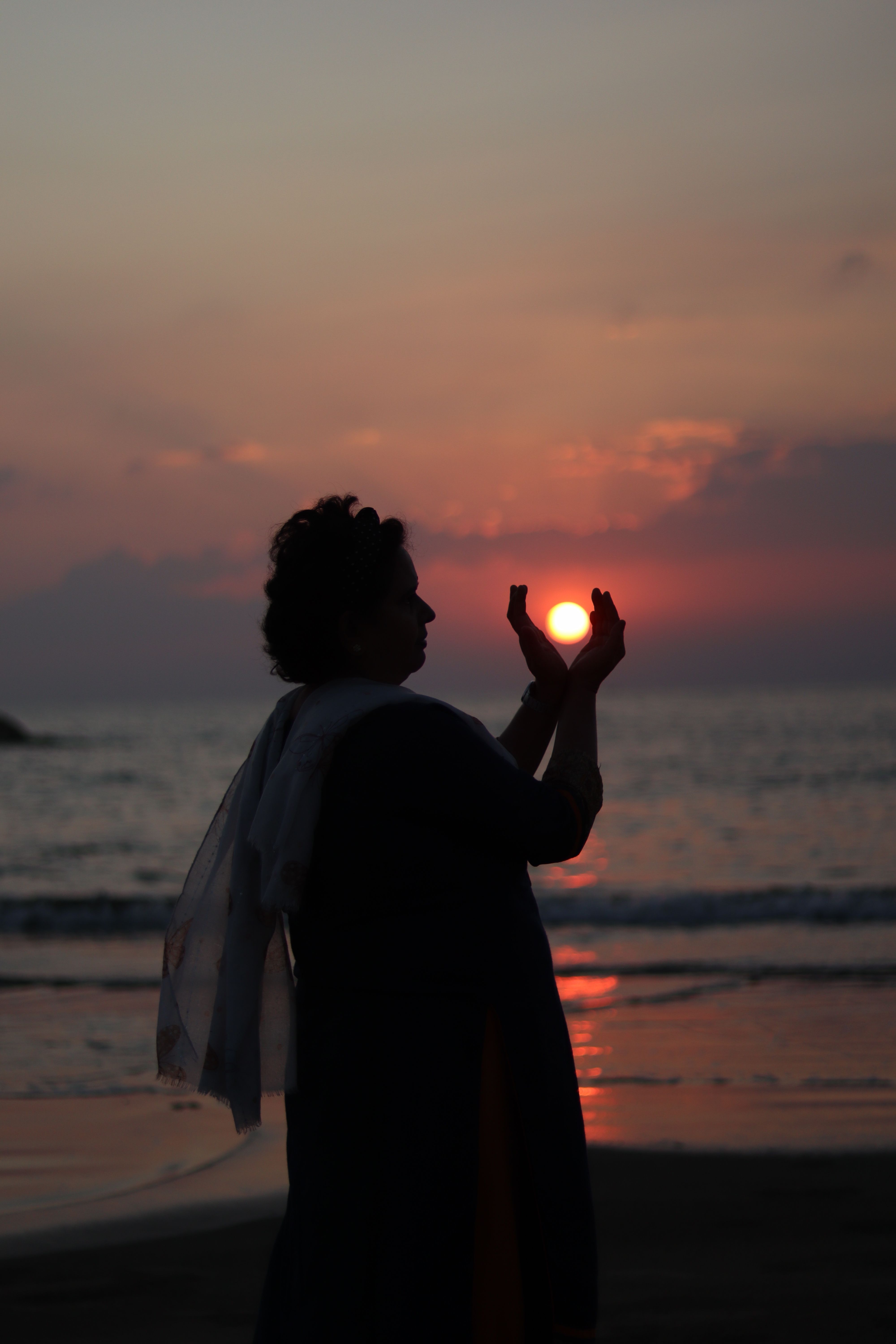 Captivating silhouette of a woman posing with the sunset at the seashore, creating a serene and artistic vibe.