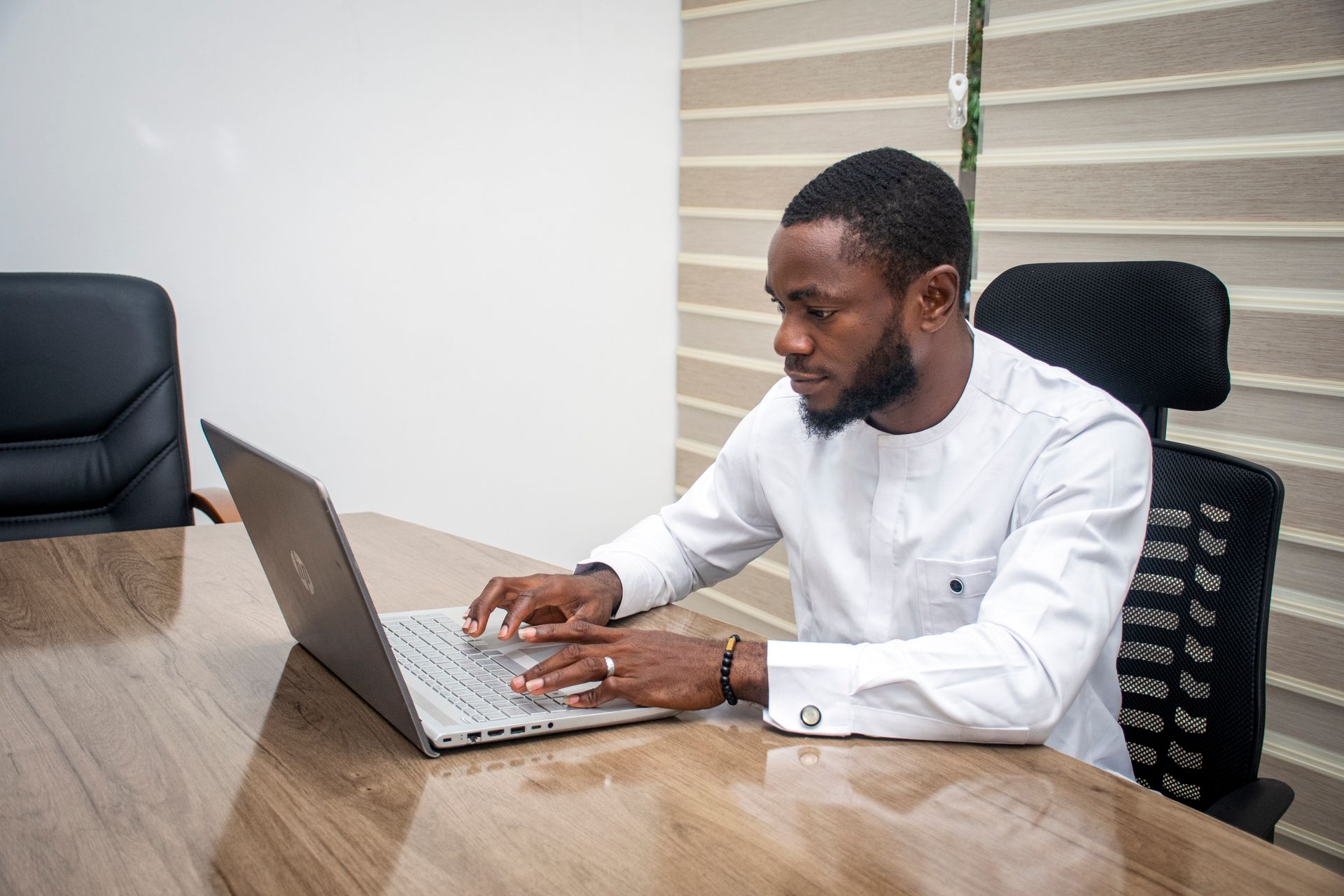 Stylish African man in a modern office using a laptop for business tasks.