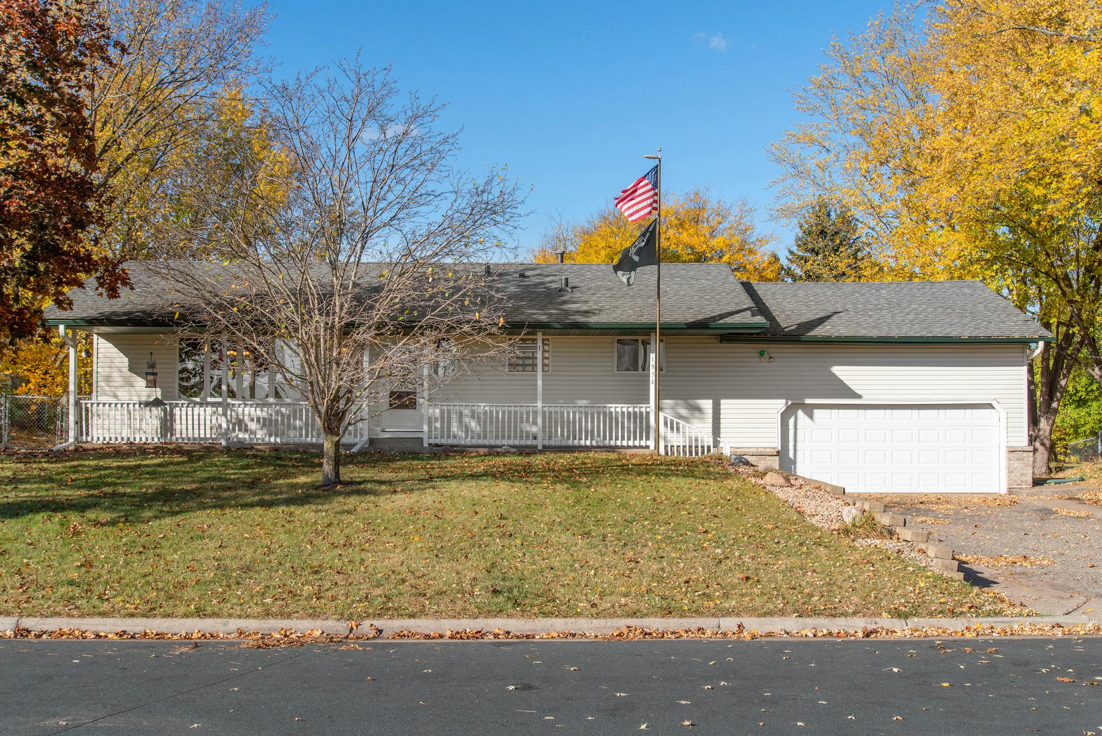 USA pride suburban house A cozy suburban house with a USA flag, surrounded by vibrant autumn trees, showcasing American pride.