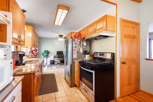 Free Spacious kitchen showcasing wooden cabinets, stainless steel appliances, and home office space. Stock Photo