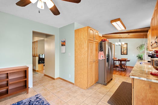 Bright kitchen with wooden cabinets, stainless fridge, and dining area.