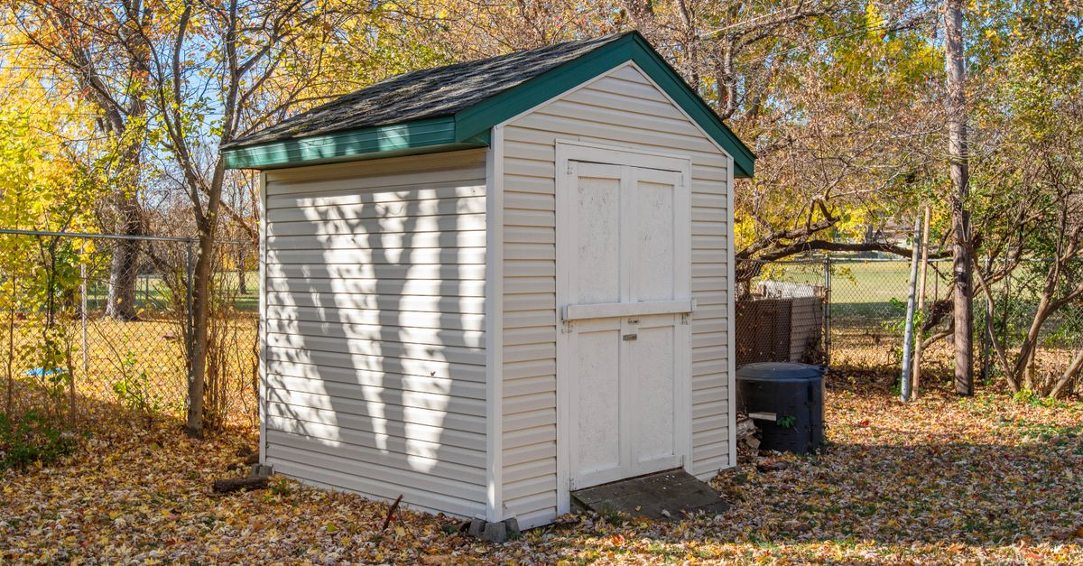 A quaint backyard shed surrounded by autumn foliage, ideal for storage solutions.