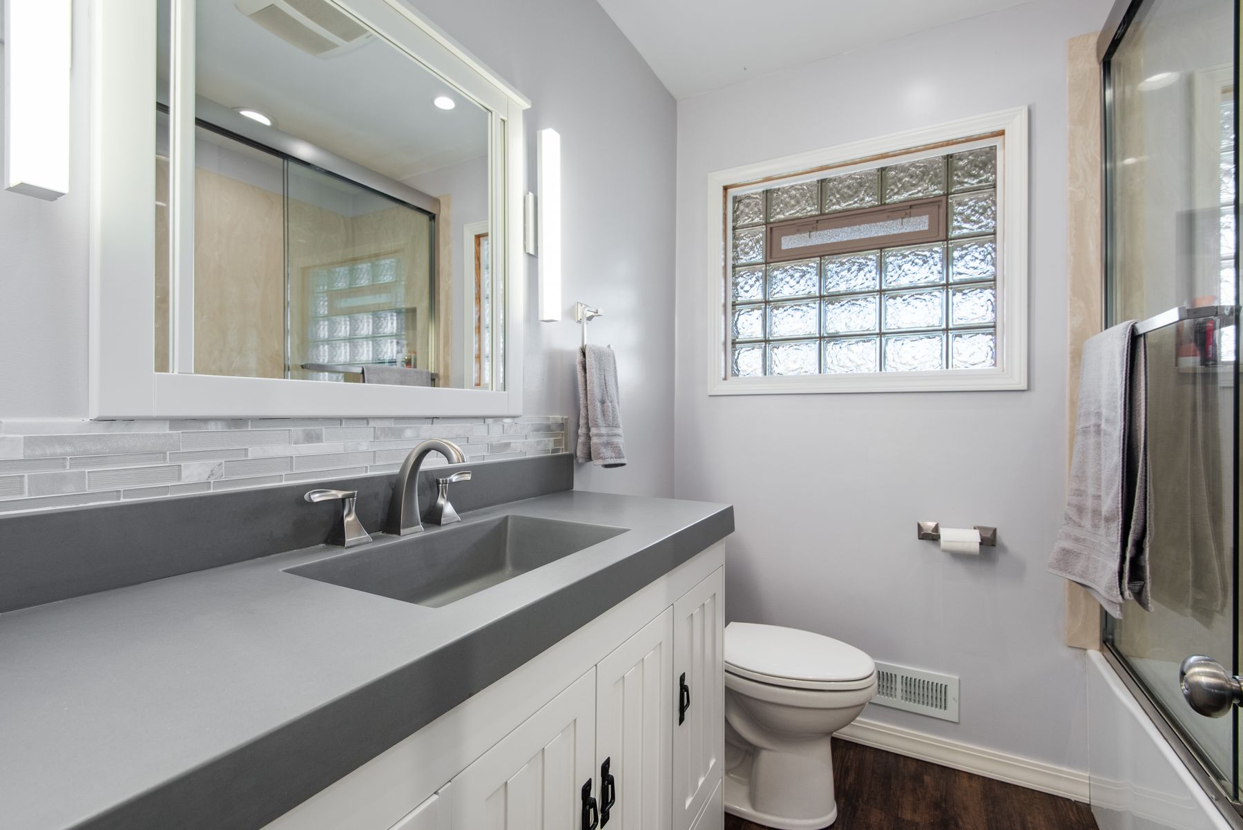 Modern bathroom with grey vanity, mirror and glass shower