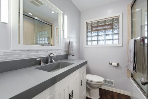 Free Sleek modern bathroom featuring a gray vanity, elegant mirror, and glass shower door. Stock Photo