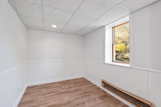 Bright empty room with wooden floor and window. Ideal for real estate or renovation projects.