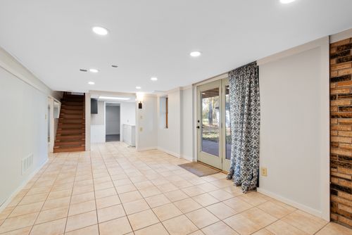 Free Bright and empty basement with tile flooring and glass doors leading outside. Stock Photo
