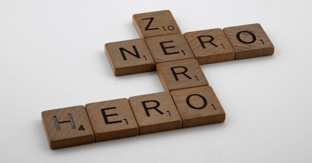 Wooden Scrabble tiles displaying words 'Hero' and 'Zero' on a white surface.