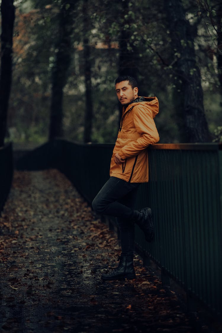 Man Leaning On Metal Handrails Wearing Yellow Windbreaker Jacket 