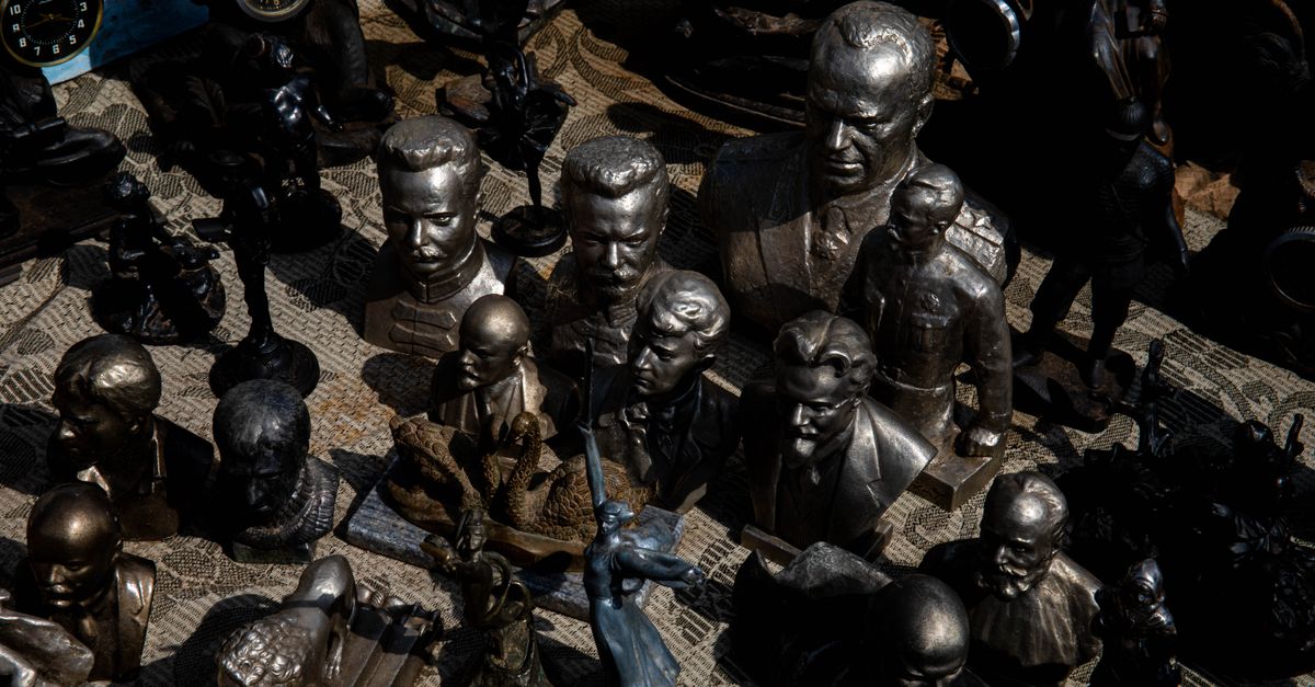 Diverse array of bronze sculptures and busts displayed outdoors, casting intricate shadows.