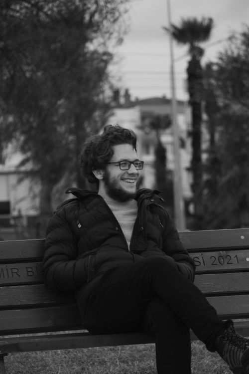 Free Black and white portrait of a man smiling on a park bench in İzmir, Turkey. Stock Photo