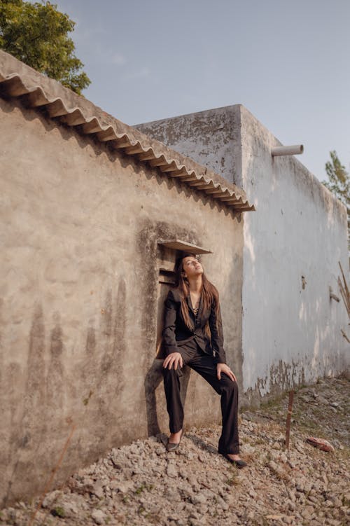 Free Woman in Black Long Sleeve Shirt and Black Pants Sitting on Concrete Wall Stock Photo