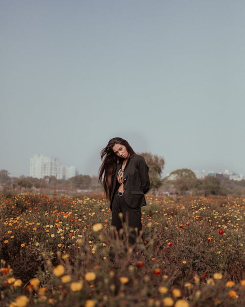 Free Woman Wearing Black Blazer Standing on a Flower Field Stock Photo