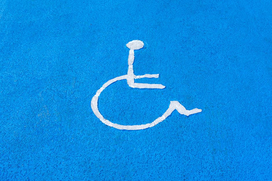 Clear blue disabled parking sign on asphalt surface, symbolizing accessibility.