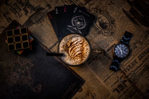 Free Top view of coffee, vintage watch, Rubik's cube, and cards on old newspaper. Stock Photo