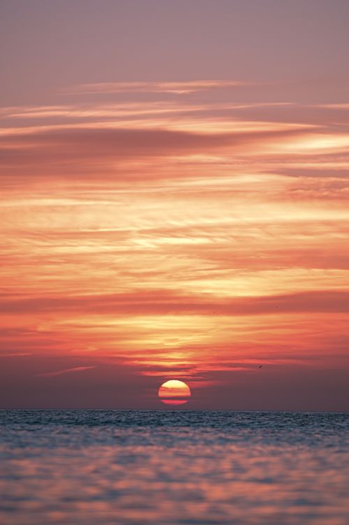 Free Capture the serene beauty of a vibrant sunset over a calm ocean horizon, with warm hues and gentle waves creating a soothing scene. Stock Photo