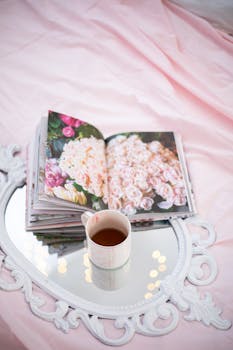 Elegant setup with floral book and tea on ornate mirror, perfect for a calming retreat.