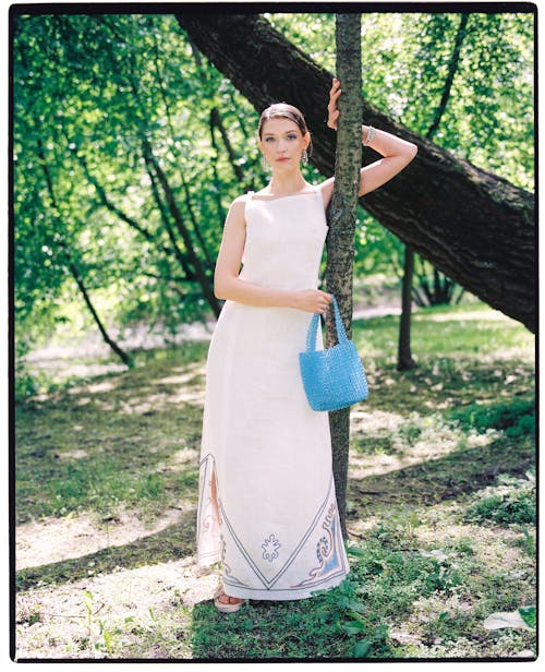 Woman in White Sleeveless Dress Standing on Brown Tree Trunk