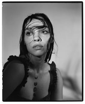 Moody black and white portrait of a woman with wet hair and thoughtful expression.