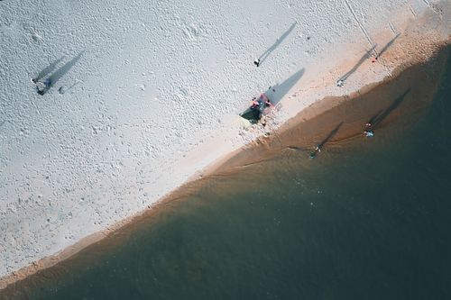 Free Drone shot capturing beachgoers' shadows on Chukai's sandy shores, Terengganu. Stock Photo