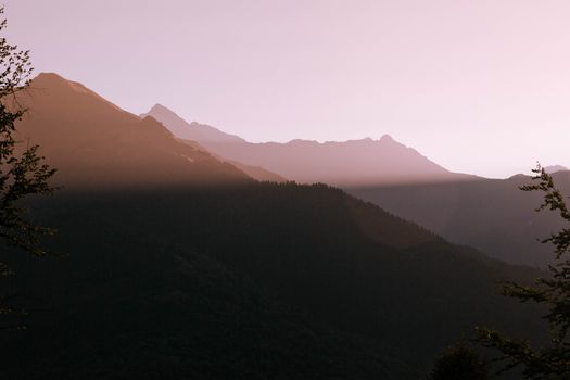 Serene mountain view at dusk with silhouette of peaks and soft pastel tones.