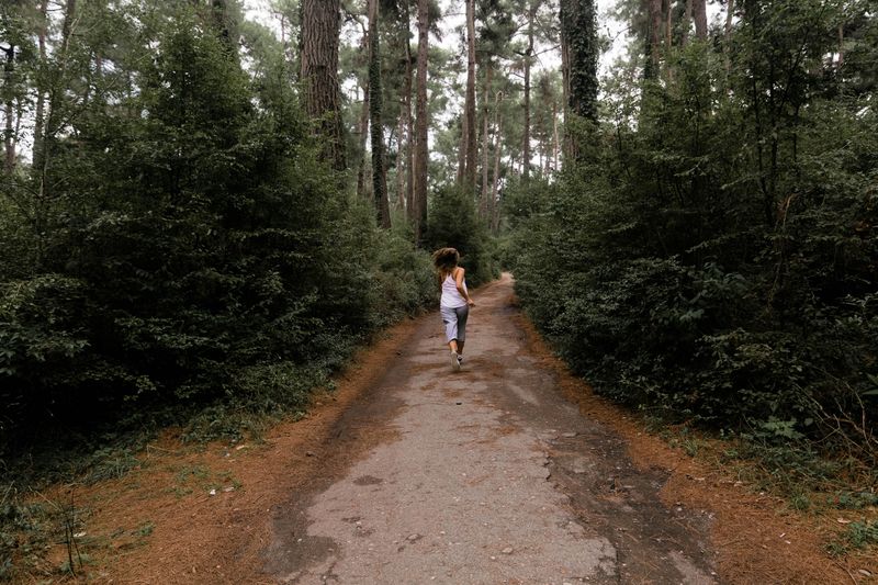 Runner seen from behind on a dirt path in a green forest
