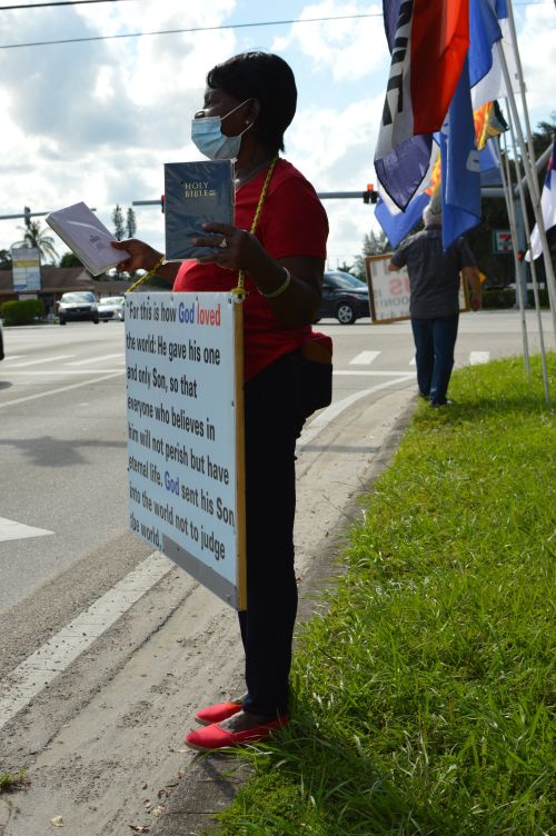 Free Woman holding a Bible and sign promoting a religious message on a street corner. Stock Photo