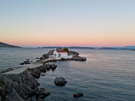 Scenic view of a coastal chapel at sunset with calm seas in Sikiada, Greece.