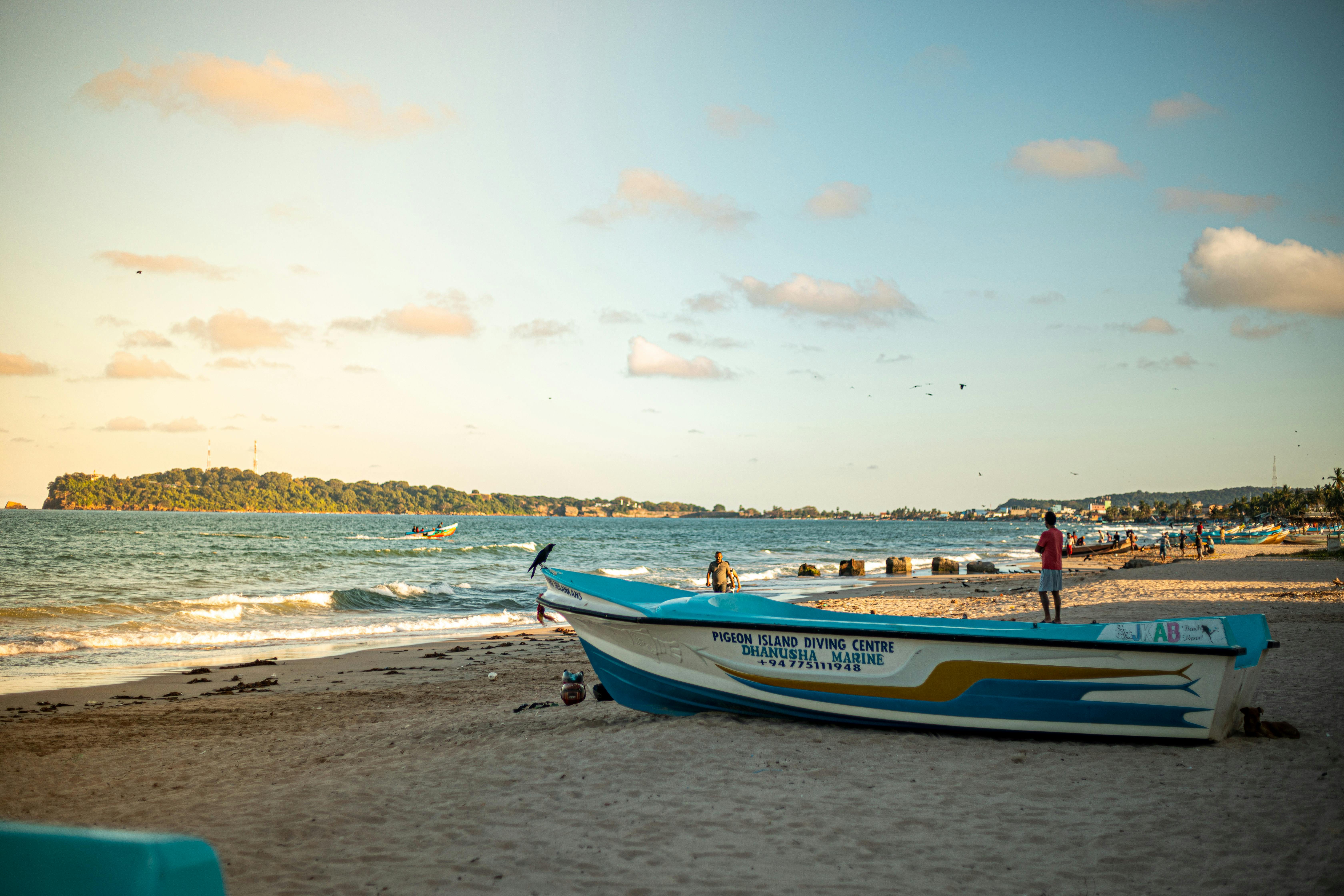 A tranquil beach in Trincomalee, Sri Lanka with boats and people enjoying the serene scenery in the evening light. - ¿Dónde dormir en Trincomalee?