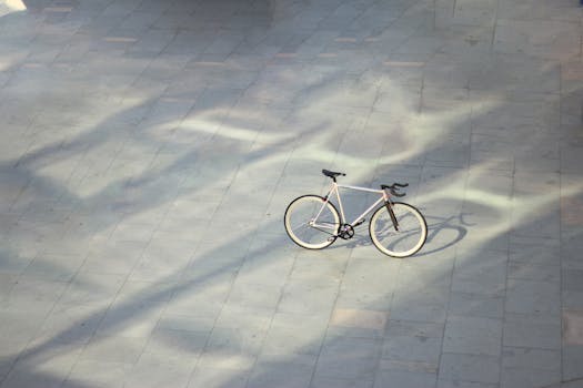 A lone bicycle parked on a sunlit pavement casting shadows.