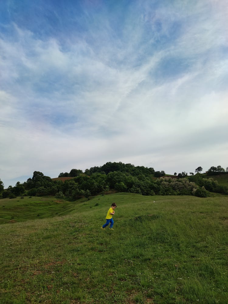 A Kid Running On The Grass Field