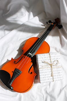 Bright image of a violin paired with a stylishly wrapped gift on white fabric.