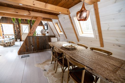 A cozy, rustic dining area in an A-frame cabin featuring wooden beams and warm accents.