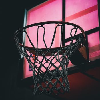 Dramatic view of a basketball hoop with a vibrant pink background, capturing the essence of the sport.