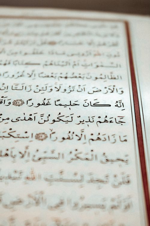 Free Detailed close-up of Arabic script with decorative elements on a paper page. Stock Photo