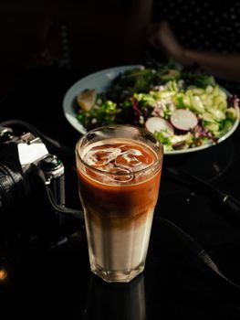 A tall glass of iced coffee paired with a fresh salad, captured in a cozy Montreal cafe.
